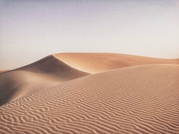 Sand dunes in desert against clear sky