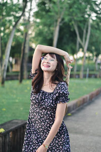 Portrait of young woman standing against trees