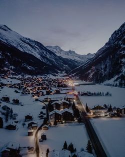Aerial shot of town surrounded by snowcapped mountains at dusk during winter