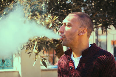 Mature man smoking while standing against plants