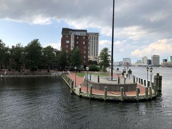 Boats in river by buildings against sky