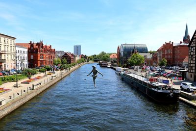 View of river amidst buildings in city against sky