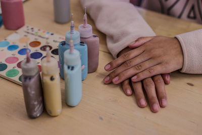 Cropped hands of woman by watercolor paints at table