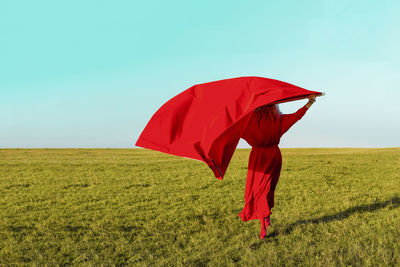 Red umbrella on field against sky