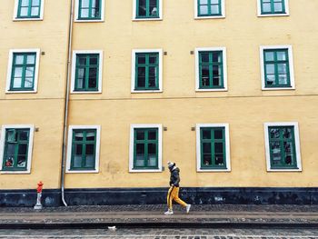 Side view of people walking on street by building