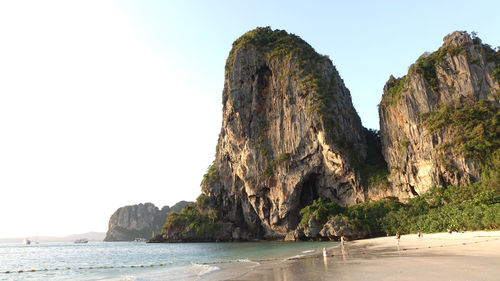 Rock formation on sea against clear sky