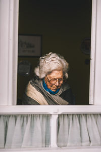 Portrait of smiling woman looking through window at home