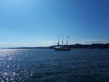 Sailboat sailing in sea against blue sky