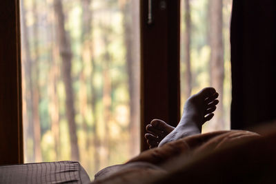 Midsection of woman relaxing on window at home