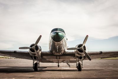 Douglas dc-3 on runway against cloudy sky