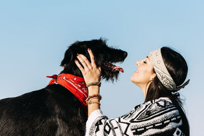 Side view of woman playing with dog against sky