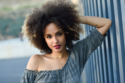 Close-up portrait of woman with curly hair by wall