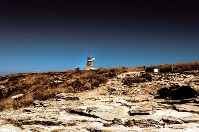 Lighthouse on street amidst buildings against clear sky