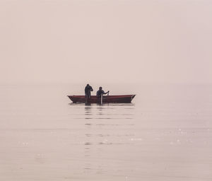 Men sitting on boat in sea against sky