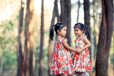 Twin sisters standing in forest