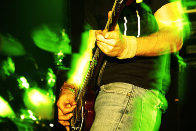 Midsection of man playing guitar