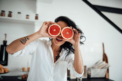 Close-up of woman holding grapefruit at home