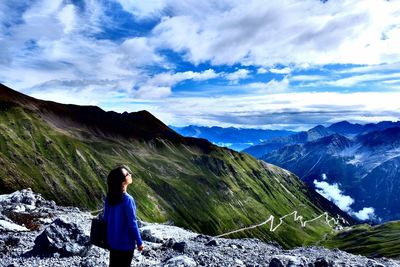 Rear view of young woman looking at mountains against sky