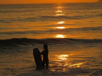 Silhouette man on beach against sky during sunset