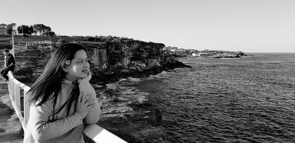 Woman looking at sea against clear sky 