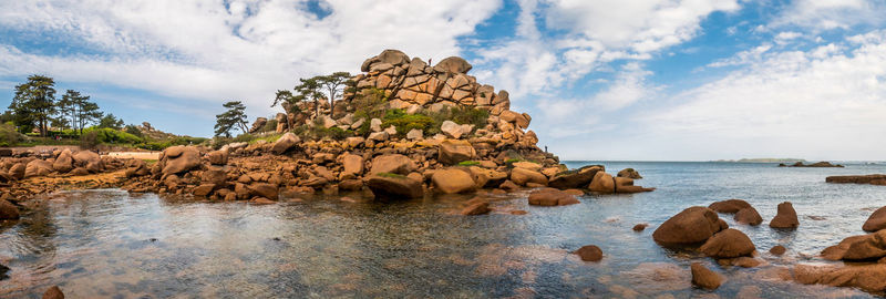 Scenic view of rocks by sea against sky