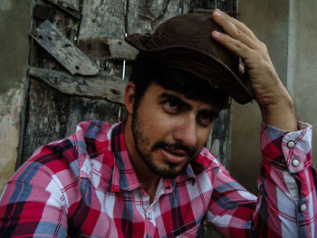 Man wearing hat looking away against old house 