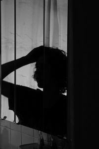 Portrait of silhouette woman standing by window