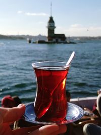 Close-up of person holding fresh turkish tea against sky