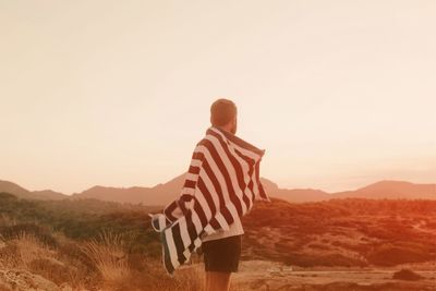 Man with striped towel standing on field against clear sky