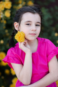 Stylish little kid girl 6-7 year old smell yellow rose flower bloom bushes in garden outdoor closeup