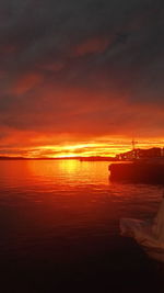 Boats moored in sea against sky during sunset