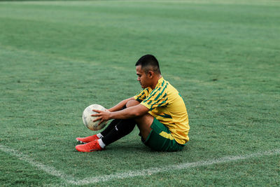 Side view of boy sitting on grass