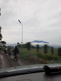 Cars on road against sky seen through car windshield