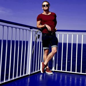 Full length portrait of young man standing against railing