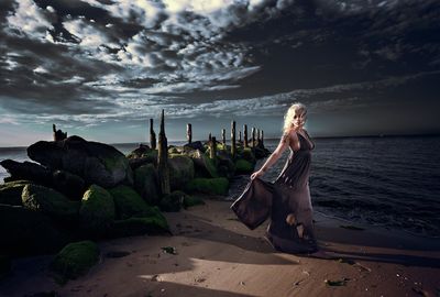 Full length of model standing on shore at beach against sky