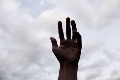 Low angle view of human hand against sky