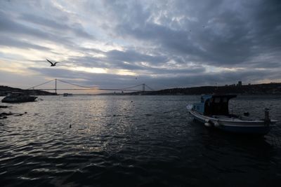 Boat sailing in sea against cloudy sky