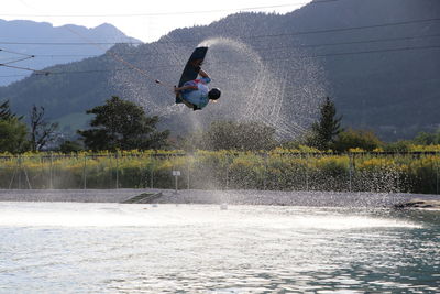 Man jumping on lake against mountain