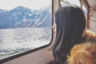 Woman looking through window during winter