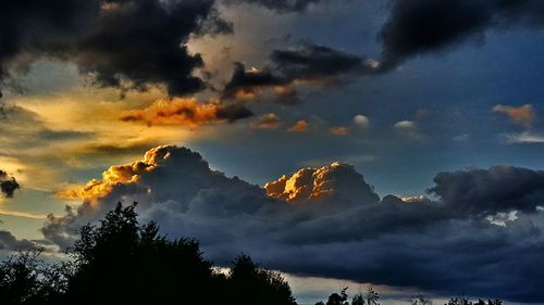 Low angle view of silhouette trees against dramatic sky