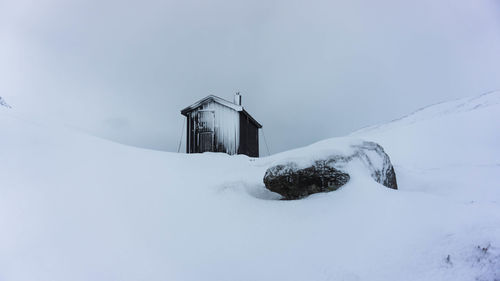 Low angle view of house on snowy field against sky