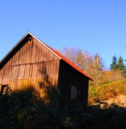 Abandoned cottage on field against clear blue sky