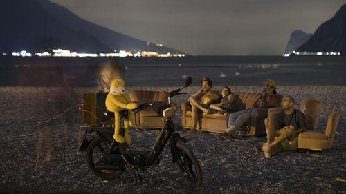 People sitting on beach by sea against sky