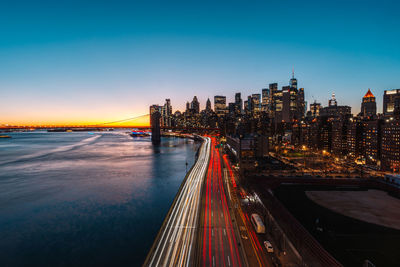 Illuminated bridge over river against sky during sunset