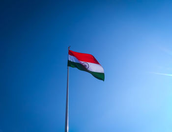 Low angle view of flag against blue sky