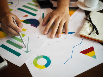 Cropped hand of business person working over graph in office