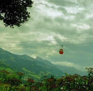 Overhead cable car over mountains against sky