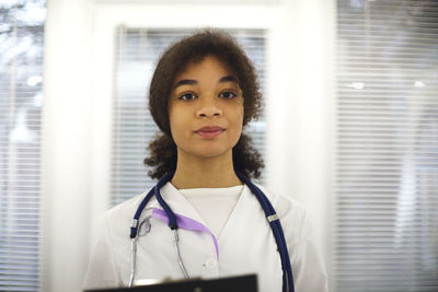 Portrait of female doctor holding stethoscope at home