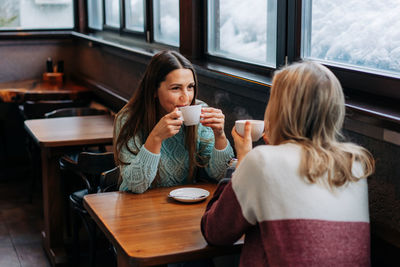 Two happy women having leisure drink tea and chat in a cafe.