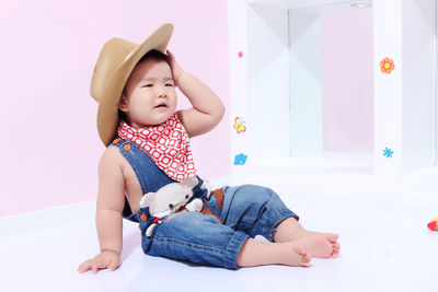 Cute boy looking away while sitting on bed at home